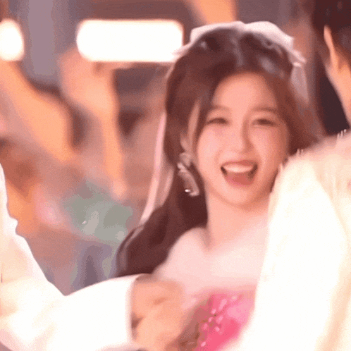 a woman in a pink dress with a white bow in her hair is smiling