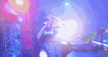 a woman is singing into a microphone on a stage with purple lights behind her