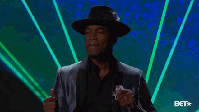 a man in a hat is holding a microphone in front of a bet sign
