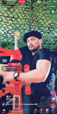 a man in a black hat is holding a toy gun in front of a green camouflage background