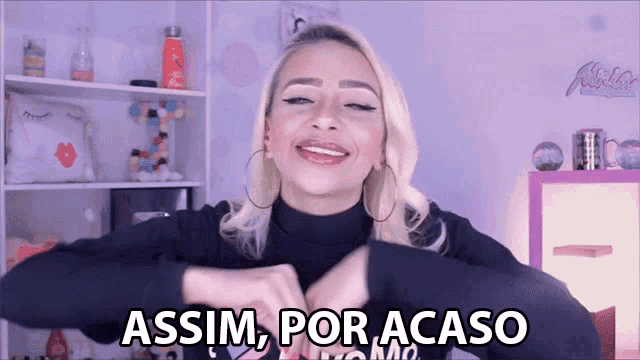 a woman is making a heart shape with her hands and the words assim por acaso are written below her