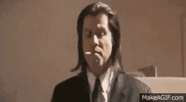 a man in a suit and tie is smoking a cigarette while sitting at a desk .