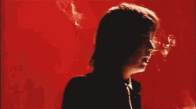 a man smoking a cigarette in front of a red background