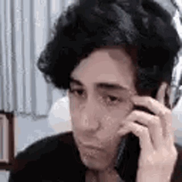 a young man is talking on a cell phone in a room .