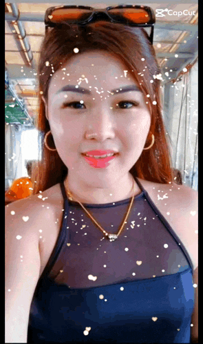 a woman wearing sunglasses and a necklace looks at the camera with hearts coming out of her eyes
