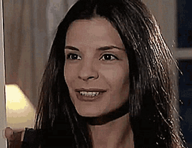 a close up of a woman 's face with long hair and a lamp in the background .