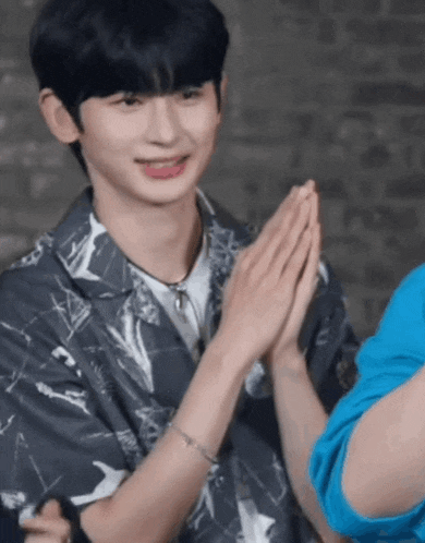 a young man in a shirt is clapping his hands together