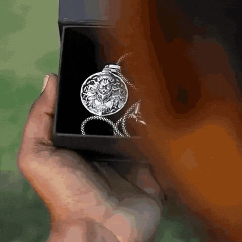 a person is holding a silver necklace in a black box