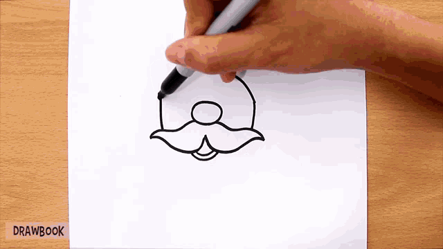 a person is drawing a mustache on a piece of paper that says drawbook on the bottom