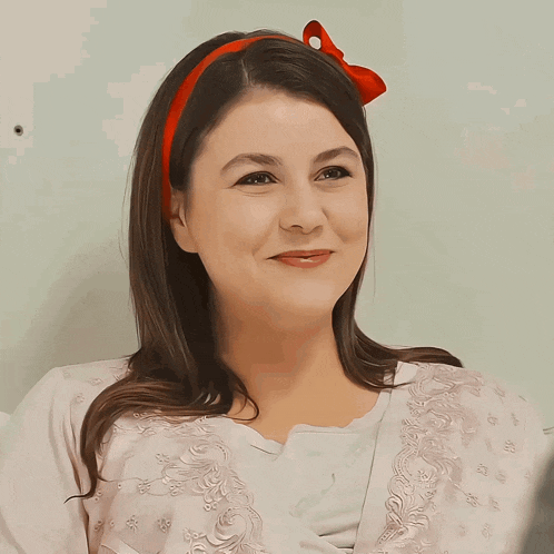 a woman wearing a red headband is smiling and looking at the camera