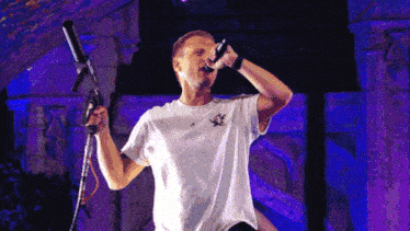a man singing into a microphone while wearing a white shirt
