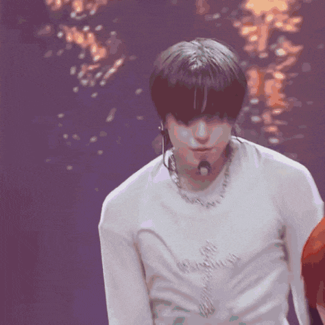 a man in a white shirt is dancing on a stage with a microphone .
