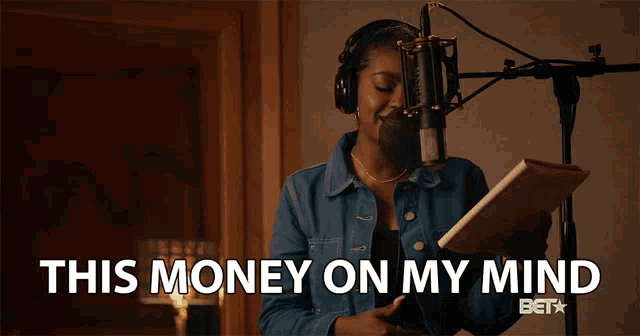 a woman singing into a microphone with the words " this money on my mind " above her