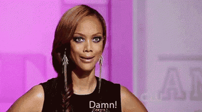 a woman wearing a black tank top and earrings is making a funny face and saying `` damn '' .