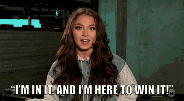 a girl with long hair is saying " i 'm in it and i 'm here to win it "