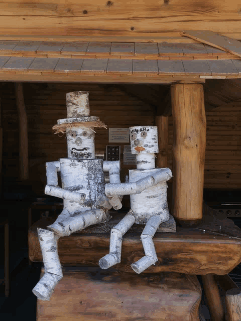two sculptures made out of birch branches are sitting on a table