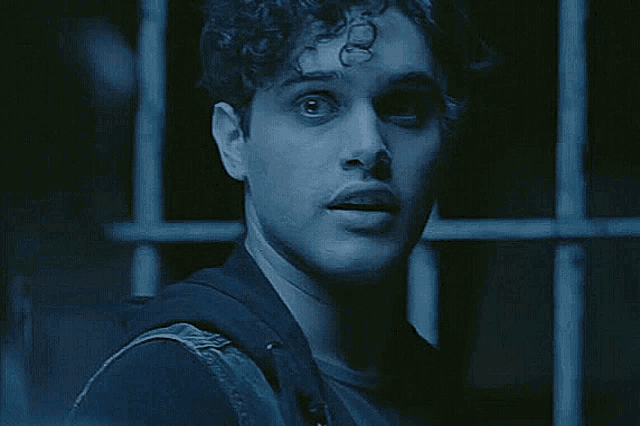 a close up of a man 's face with a surprised look on his face in a dark room .