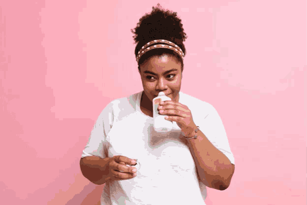 a woman is drinking from a bottle with a green label