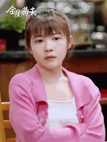 a woman wearing a pink sweater and a white tank top with chinese writing on it
