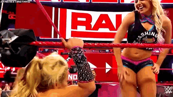 a female wrestler is standing in a wrestling ring talking to another wrestler .