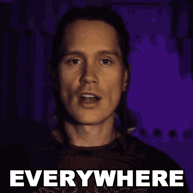 a man in a red shirt says " everywhere " in white letters