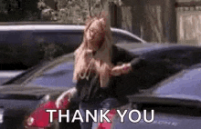 a woman is standing in front of a parking lot holding a bag and says `` thank you '' .