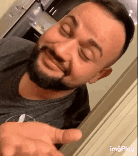 a man with a beard is making a funny face with his eyes closed in a kitchen