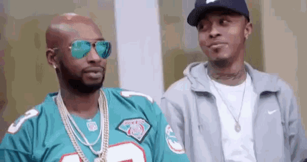 two men are standing next to each other and one of them is wearing a green jersey .