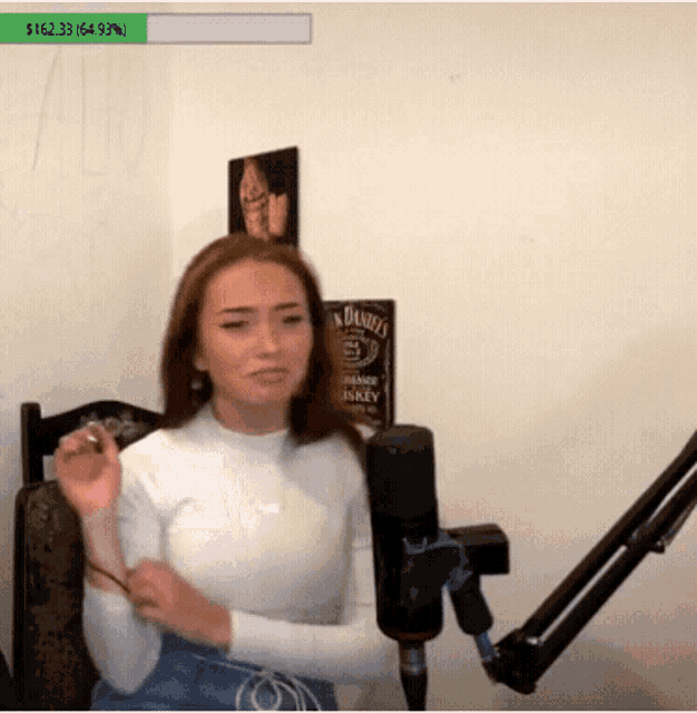 a woman is sitting in front of a microphone with a sign that says jack daniel 's on the wall behind her