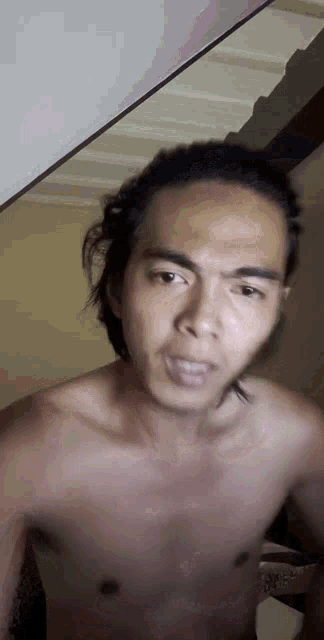 a shirtless man is standing in front of a mirror and making a funny face .