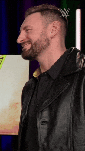 a man with a beard wearing a black shirt and black leather jacket