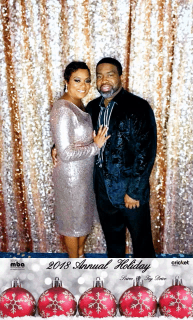 a man and a woman pose for a photo in front of a 2018 annual holiday backdrop