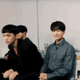 a group of young men are sitting on a couch . one of the men is smiling .