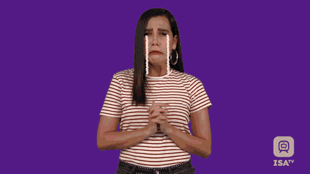 a woman in a striped shirt is crying with isa tv in the background