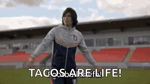 a man is standing on a soccer field with his arms outstretched and says tacosbarelife .