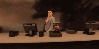 a man in a suit is standing at a counter in front of a computer monitor ..