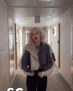 a woman standing in a hallway with the letter s on the bottom right