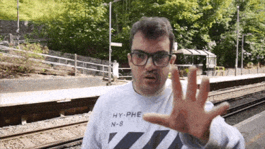 a man wearing glasses and a hy-phe n-8 shirt