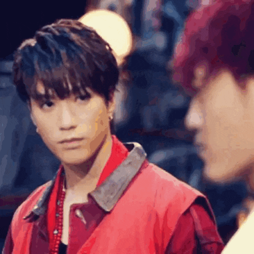 a man in a red jacket is standing next to another man in a red jacket .