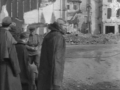 a black and white photo of soldiers standing in front of a destroyed building ..