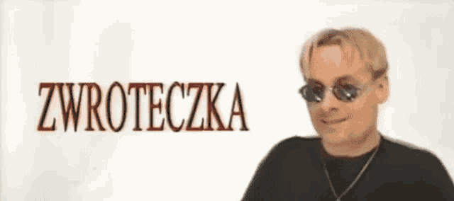 a man wearing sunglasses and a black shirt is standing in front of a white background with the word zwrotecka written on it .