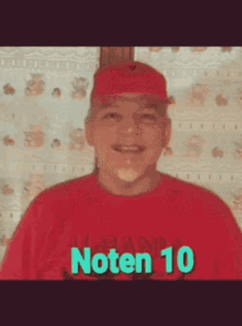 a man wearing a red shirt that says noten 10 is smiling