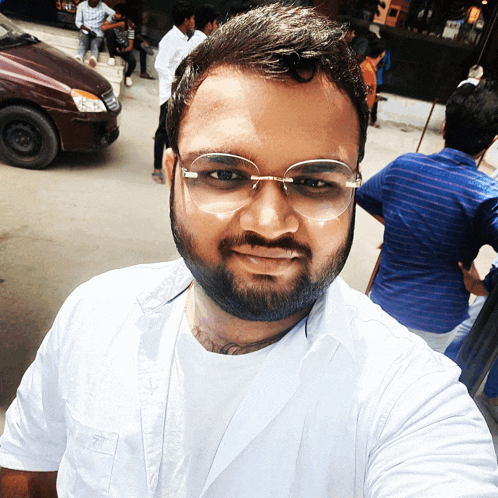 a man wearing glasses and a white shirt is smiling