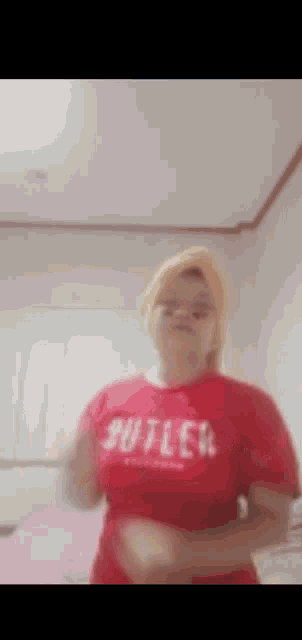 a woman is wearing a red shirt that says ' butler ' on it