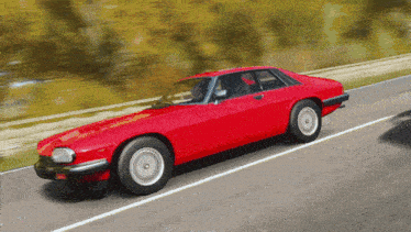 a red car is driving down a road
