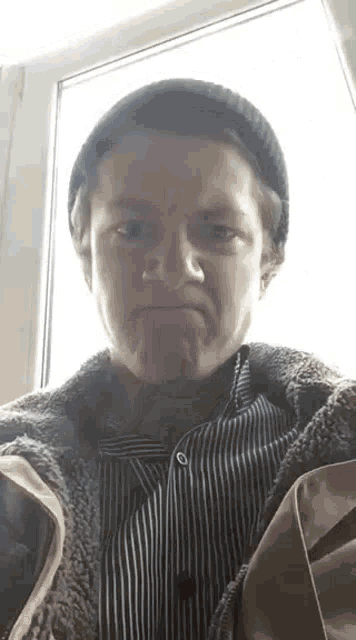 a man wearing a beanie and striped shirt is making a funny face .
