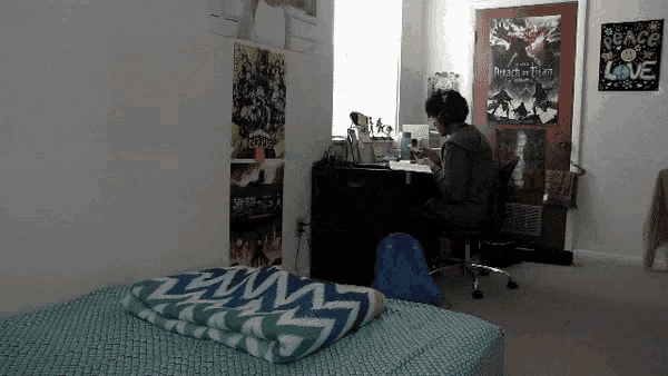 a man sits at a desk in a room with posters on the wall including one that says peace love