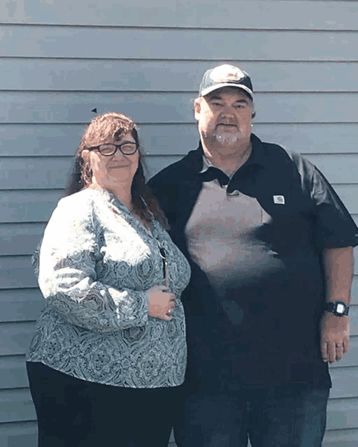 a man and a woman are posing for a picture and the man is wearing a shirt that says ' work ' on it