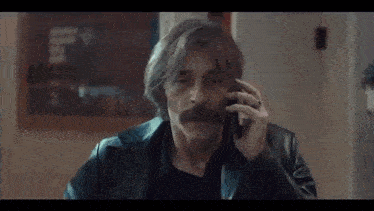 two men are talking on a cell phone in a store .