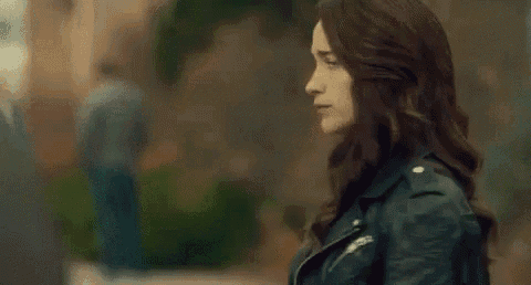 a woman with her eyes closed is wearing a black leather jacket and a green shirt .